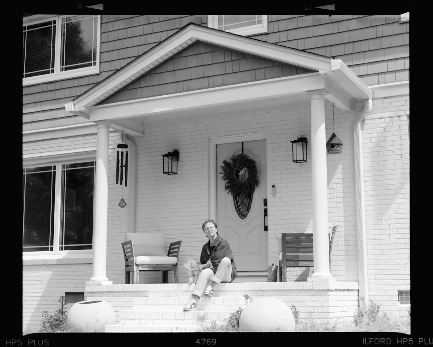 Someone sitting on the front porch steps of a family home